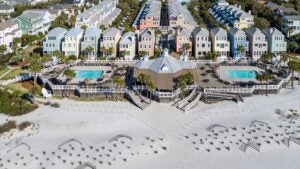 row of hotels, with pools on the beach, trees surrounding it